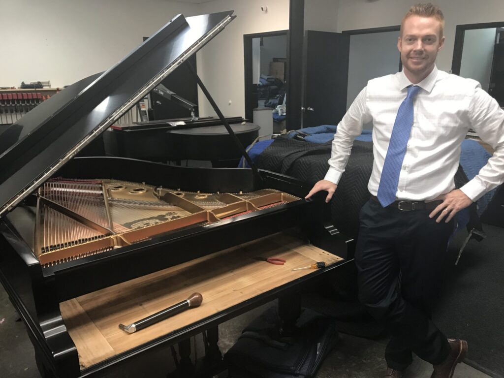 Holt Bradfield evaluating a Steinway grand piano during restoration work at Bradfield Piano in Dallas Texas